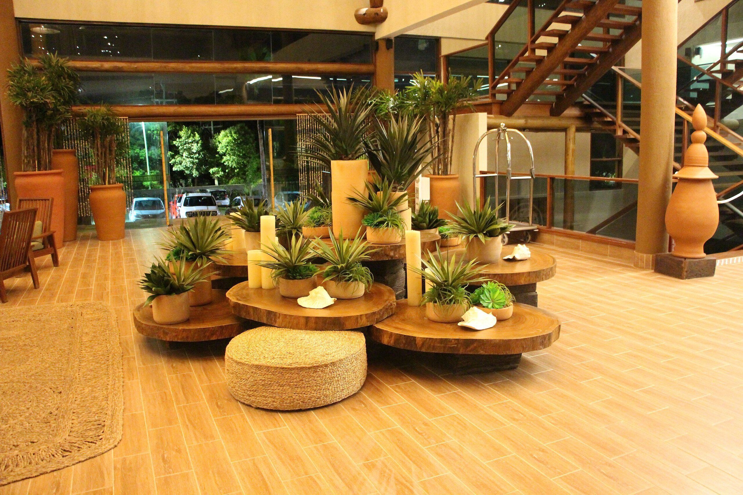 Eine Lobby mit runden Holztischen, Blumentöpfen und einer Treppe.
