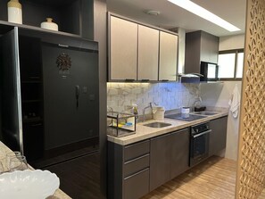 A modern kitchen with a refrigerator, oven, sink, and cabinets. -  Polinesia Resort - Porto de Galinhas - Acesso ao Hotel Samoa.  (Ipojuca)