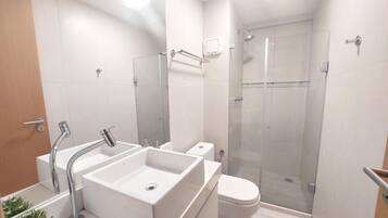 Un baño moderno con un lavabo grande, inodoro y ducha con mampara de vidrio.