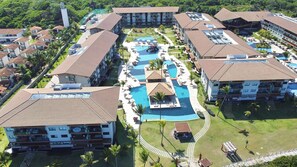 A resort with multiple buildings, a central swimming pool, and surrounding greenery. -  Polinesia Resort - Porto de Galinhas - Acesso ao Hotel Samoa.  (Ipojuca)