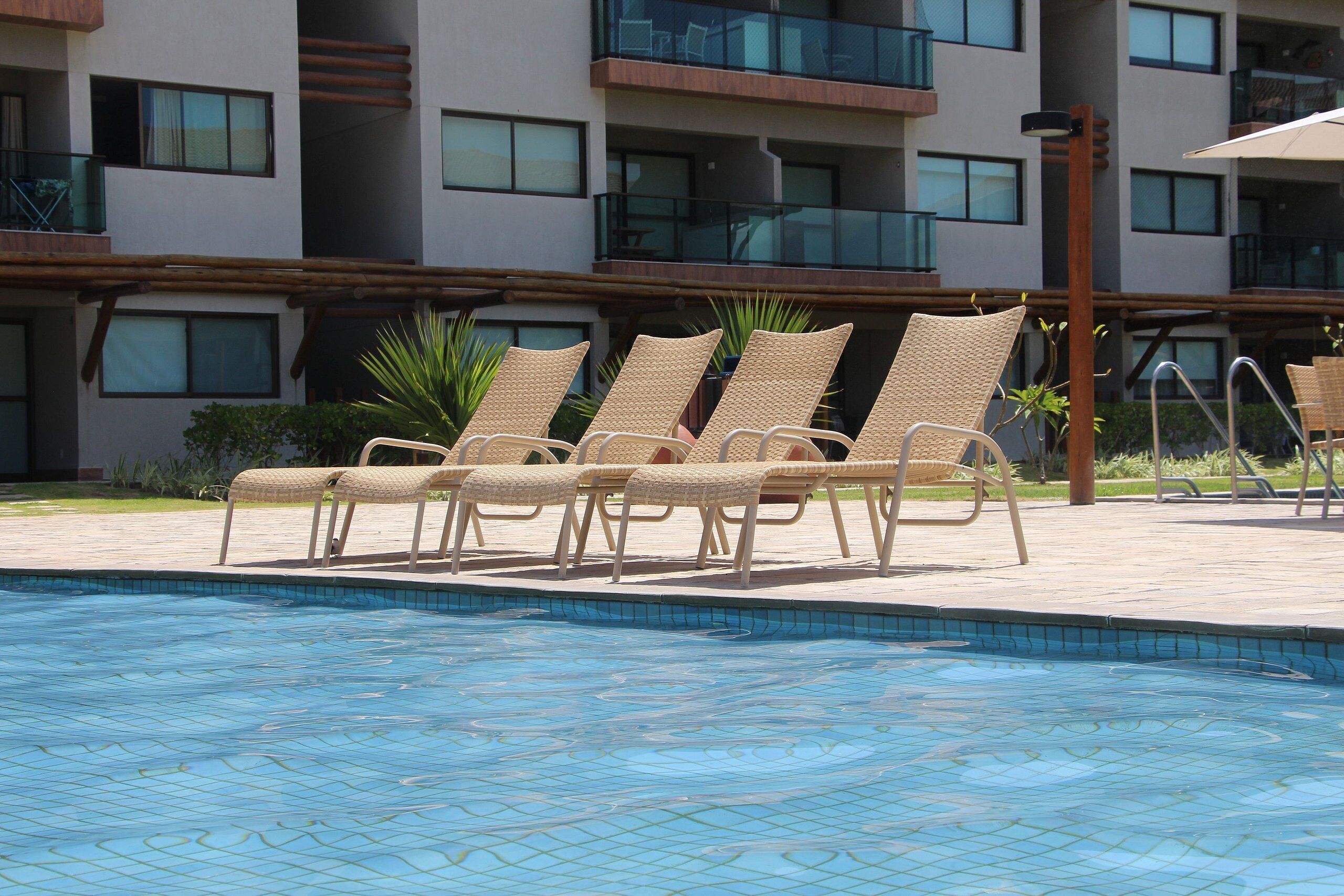Ein Swimmingpool mit Liegestühlen und ein Gebäude mit Balkonen im Hintergrund.