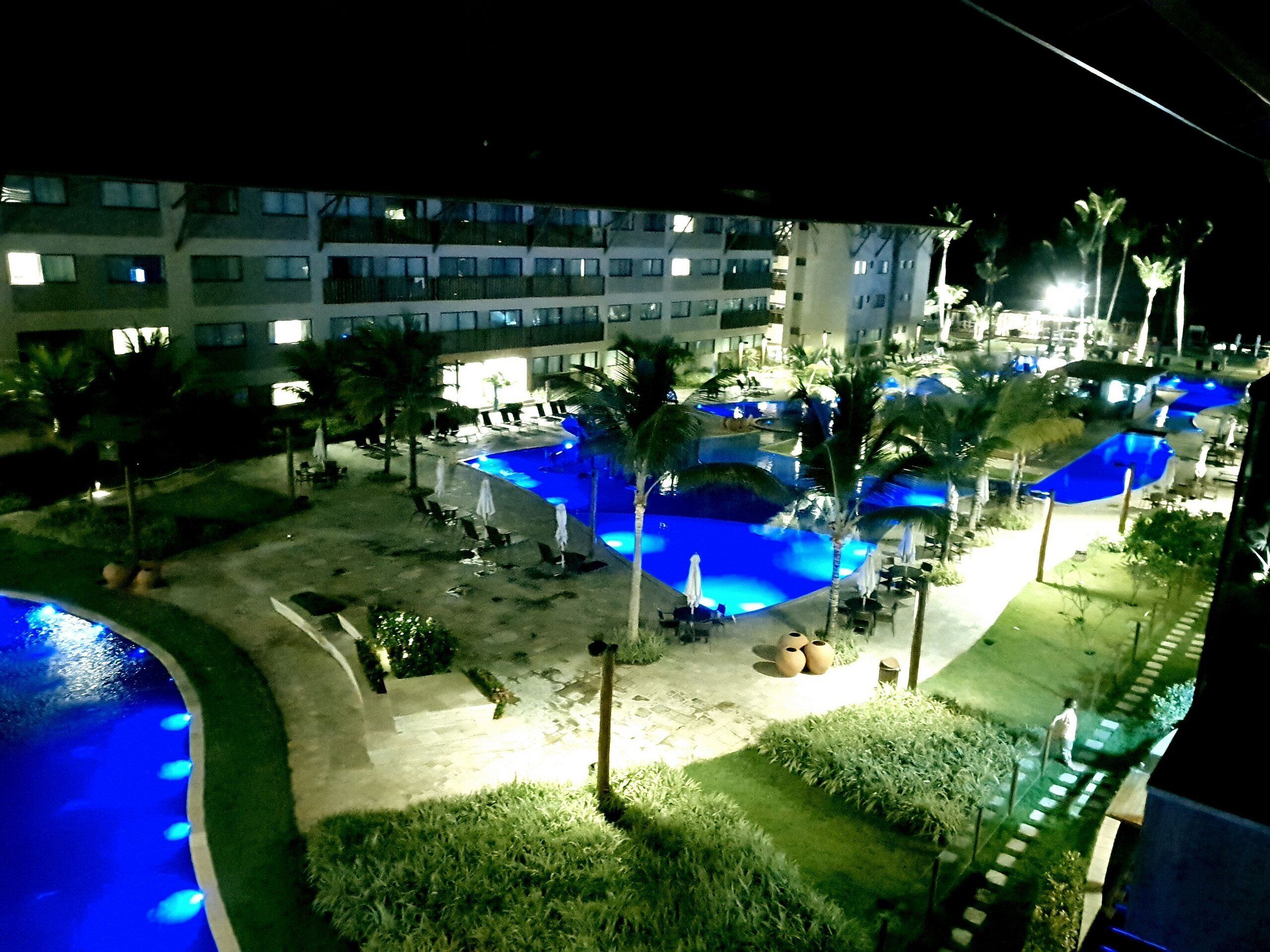 A hotel with multiple swimming pools, palm trees, and lounge chairs.
