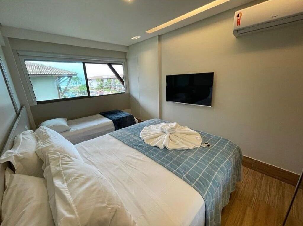 A hotel room with a bed, a TV, and a window.