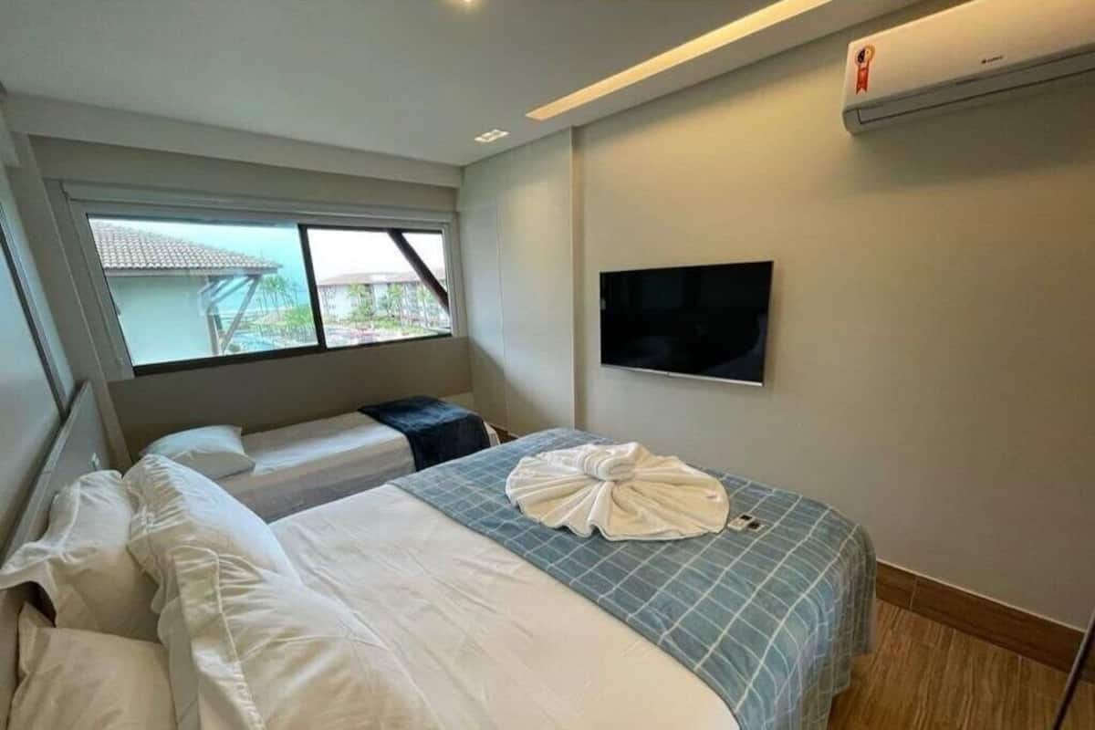 A hotel room with a bed, a TV, and a window.