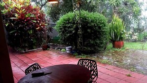 A garden area with a red tiled patio, a round table, and chairs. - Quinta Kartagus (Santa Tecla)