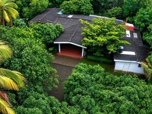 A house surrounded by dense greenery, with a covered porch and a satellite dish. - Quinta Kartagus (Santa Tecla)