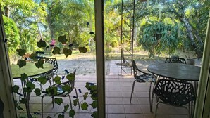An outdoor patio with a round table and chairs, surrounded by lush greenery and trees. - Quinta Kartagus (Santa Tecla)