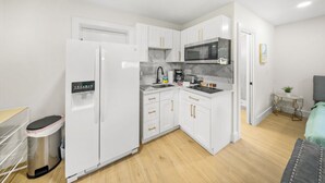 A compact kitchen with white cabinets, a refrigerator, a microwave, and a sink.