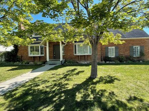 A two-story brick house with a front porch, a tree in front, and a well-maintained lawn. - Beautiful Modern Farmhouse near Sundance/BYU (Orem)