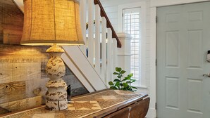 Una escalera con barandilla de madera, una lámpara y una planta cerca de una puerta.