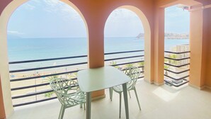 A balcony with a table and chairs, overlooking a beach and the sea. - A step away from the beach, first line, incredible views brand new! (Puerto de Mazarrón)