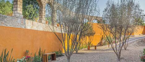 A courtyard with a brick archway, a bench, and a variety of plants.
