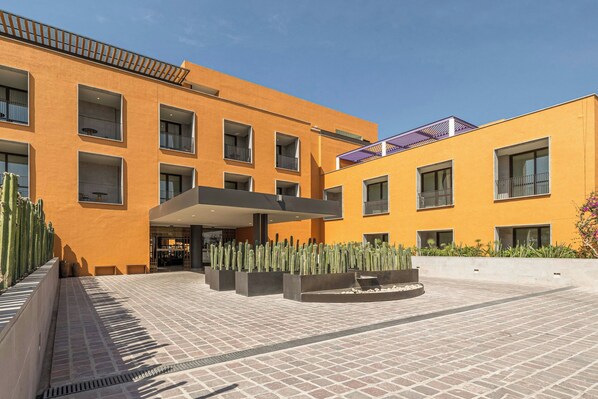 Un edificio moderno con varios balcones y un patio con cactus.