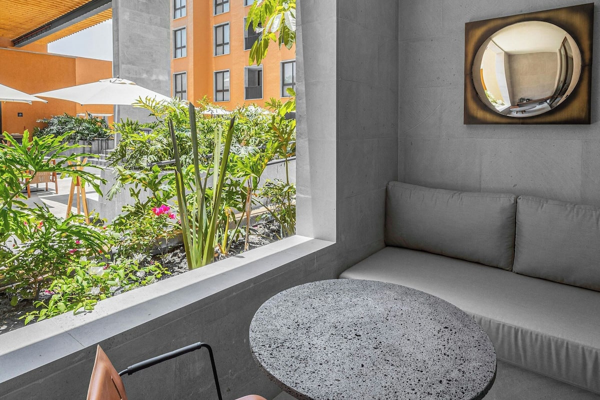 Una habitación moderna con un gran ventanal, una mesa redonda, un sofá y una silla.