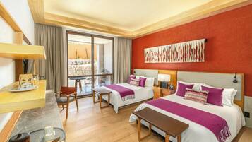 A hotel room with two beds, a desk, a chair, a table, and a large window with a view.