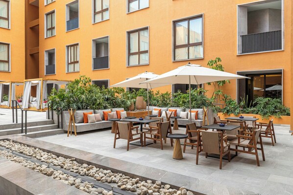 An outdoor patio area with seating arrangements, tables, and umbrellas.