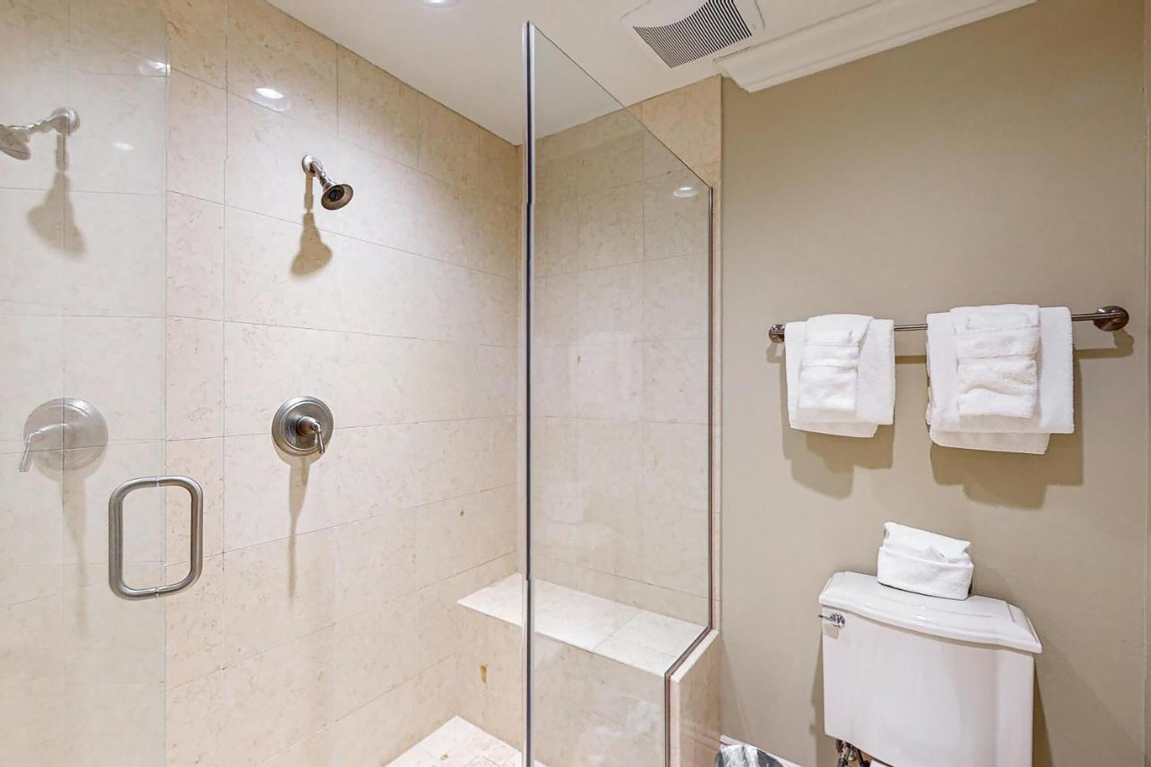 Ein modernes Badezimmer mit einer Duschkabine, einer Toilette mit Handtuchhalter und einer kleinen Ablagefläche.