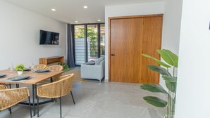 Een moderne eethoek met een houten tafel, rieten stoelen en een bank.