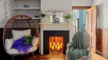 A cozy living room with a fireplace, wicker chair, and a green throw blanket.