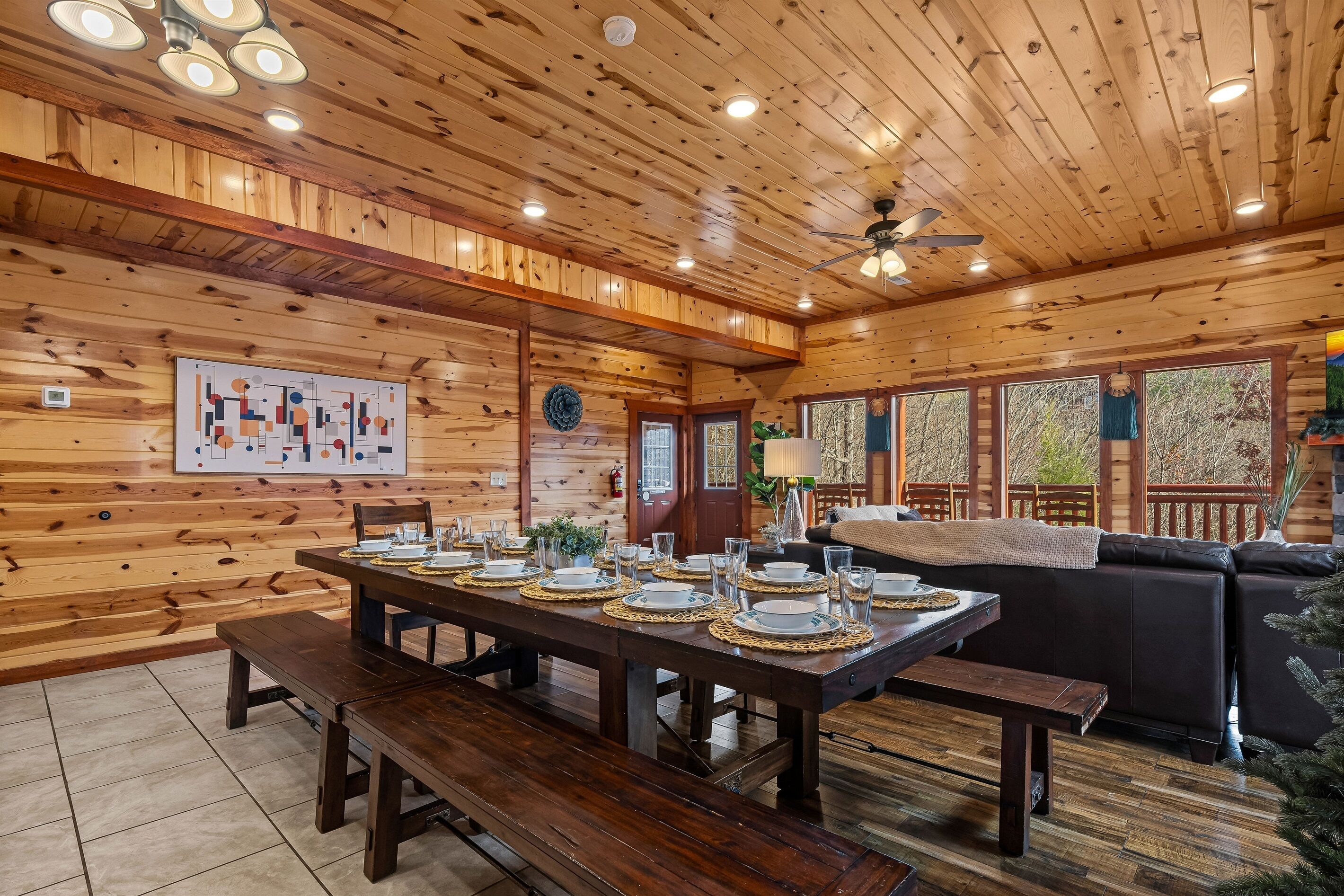 Un intérieur en bois avec une table à manger pour quatre personnes, un canapé et un ventilateur de plafond.