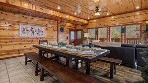 A wooden interior with a dining table set for four, a sofa, and a ceiling fan. - Pvt Indoor Pool, Gorgeous 6-BR Cabin, Theater, BBQ (Sevierville)