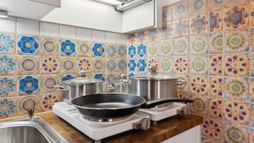 Een keuken met kleurrijke tegels, een fornuis, pannen en een spoelbak.