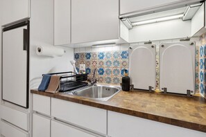 A modern kitchen with a stainless steel sink, white cabinets, and a patterned backsplash.