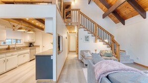 A modern interior with a kitchen, living area, and wooden staircase. - Peaceful Tahoe Retreat by Avantstay Cozy Modern Cabin Sauna, Hot Tub + Fireplace Near Lake (Carnelian Bay)