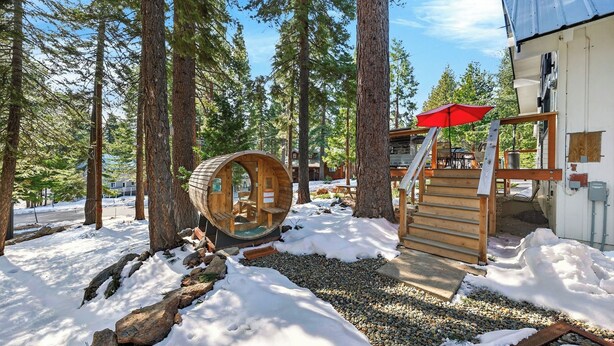 A cabin with a wooden exterior, a red umbrella, and a stone pathway. - Peaceful Tahoe Retreat by Avantstay Cozy Modern Cabin Sauna, Hot Tub + Fireplace Near Lake (Carnelian Bay)