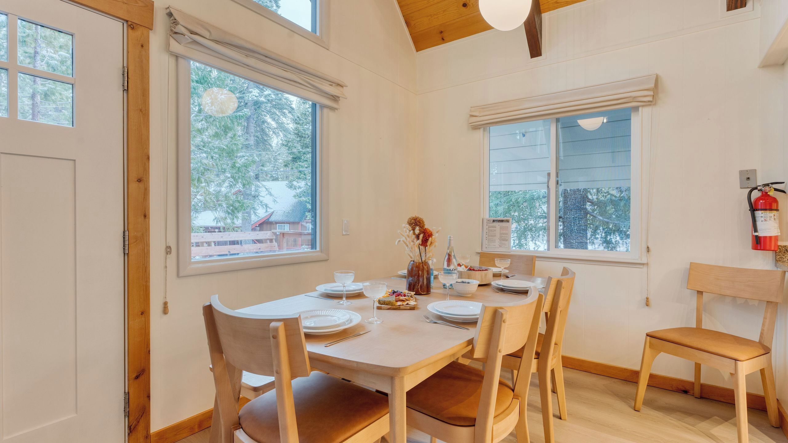 A dining area with a wooden table set for four, surrounded by chairs.