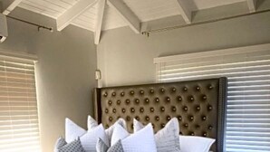A bedroom with a large bed, a tufted headboard, and a modern design. - Keepsake Oasis, Mid-Island 3-Bed Modern Cozy Home with AC, WiFi, Quiet Residence (Christiansted)
