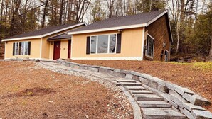 A two-story house with a stone staircase leading to the front door. - Charming 2-bedroom house with AC, WiFi in North Conway (North Conway)