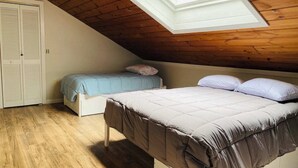 A bedroom with a sloped ceiling and a skylight, featuring two beds with different bedding. - Charming 2-bedroom house with AC, WiFi in North Conway (North Conway)