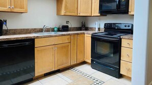 A kitchen with wooden cabinets, a black microwave, a toaster, and a stove. - Charming 2-bedroom house with AC, WiFi in North Conway (North Conway)