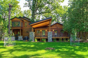 A two-story wooden cabin with a stone foundation, large windows, and a covered deck. - Short Drive to Itasca State Park - Waterfront Home (Park Rapids)