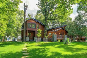 A wooden cabin with a stone foundation, surrounded by lush greenery and a clear sky. - Short Drive to Itasca State Park - Waterfront Home (Park Rapids)