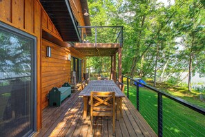 A wooden deck with a table and chairs, overlooking a grassy area with trees. - Short Drive to Itasca State Park - Waterfront Home (Park Rapids)