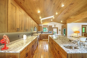 A spacious kitchen with wooden cabinets, granite countertops, and a central island with a sink. - Short Drive to Itasca State Park - Waterfront Home (Park Rapids)