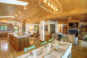 A spacious living area with a wooden ceiling, a fireplace, a television, and a dining area set up for a meal. - Short Drive to Itasca State Park - Waterfront Home (Park Rapids)