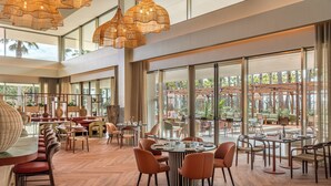Un'ampia sala da pranzo interna con soffitti alti, grandi finestre e arredi moderni.