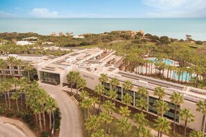 A hotel with a rooftop pool, palm trees, and a view of the sea. - Kimpton Atlantico Algarve (Albufeira)