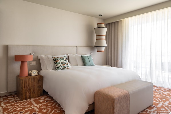 A hotel room with a large bed, a bedside lamp, a telephone, and a window with curtains. - Kimpton Atlantico Algarve (Albufeira)
