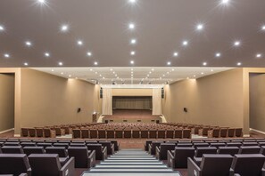 A large auditorium with rows of seats, a stage, and a ceiling with multiple lights. - Kimpton Atlantico Algarve (Albufeira)