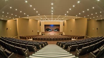 A theater with rows of seats, a stage, and a curtain.