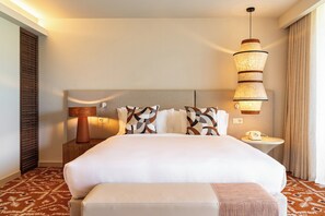A hotel room with a large bed, a bedside table with a lamp, a small table with a phone, and a patterned carpet. - Kimpton Atlantico Algarve (Albufeira)