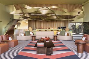 Un salon moderne avec une table basse centrale, des canapés, un tapis à motifs et un design de plafond original.