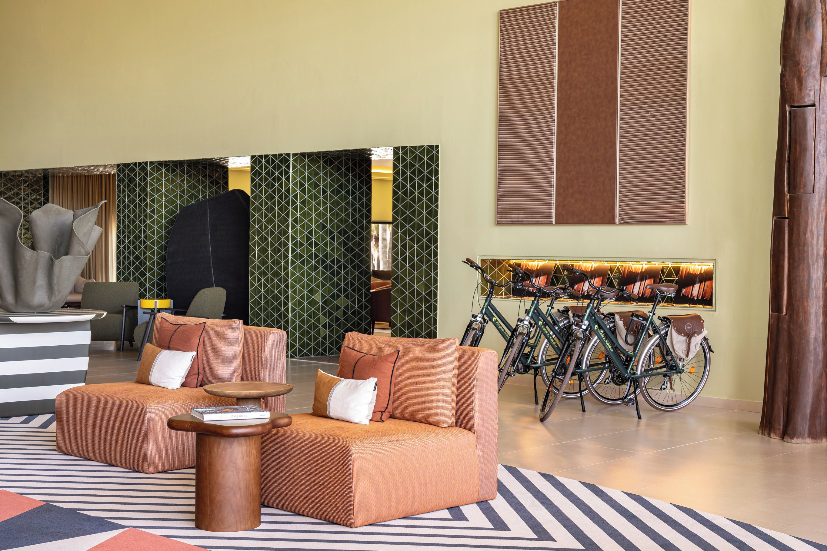 Un lobby moderno con un sofá, una mesa de centro, un soporte para bicicletas y una recepción.