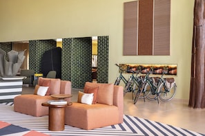A modern lobby with a sofa, a coffee table, a bike rack, and a reception desk. - Kimpton Atlantico Algarve (Albufeira)