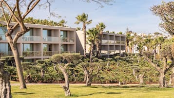 Un hôtel moderne à plusieurs étages, doté d’un jardin bien entretenu avec différentes espèces d’arbres, et offrant une vue dégagée sur les environs.