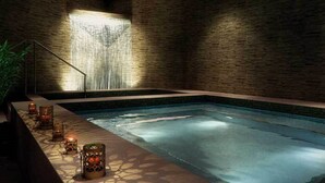 Un área de spa con piscina, cascada e iluminación con velas.